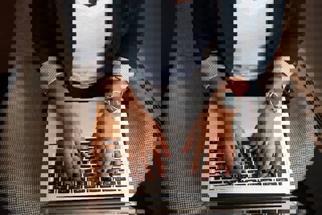 Närbild händer som skriver på laptop